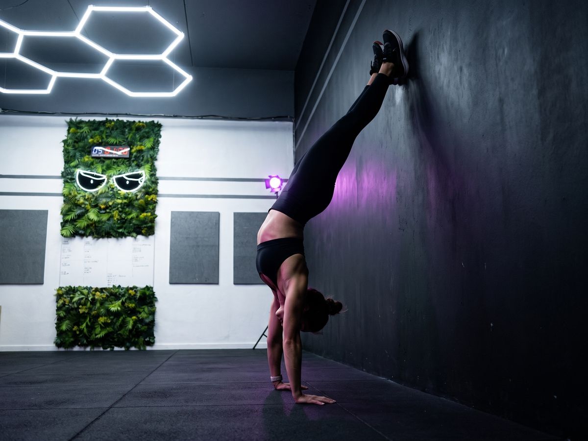 Athlète en handstand contre le mur de la salle Devil Performance