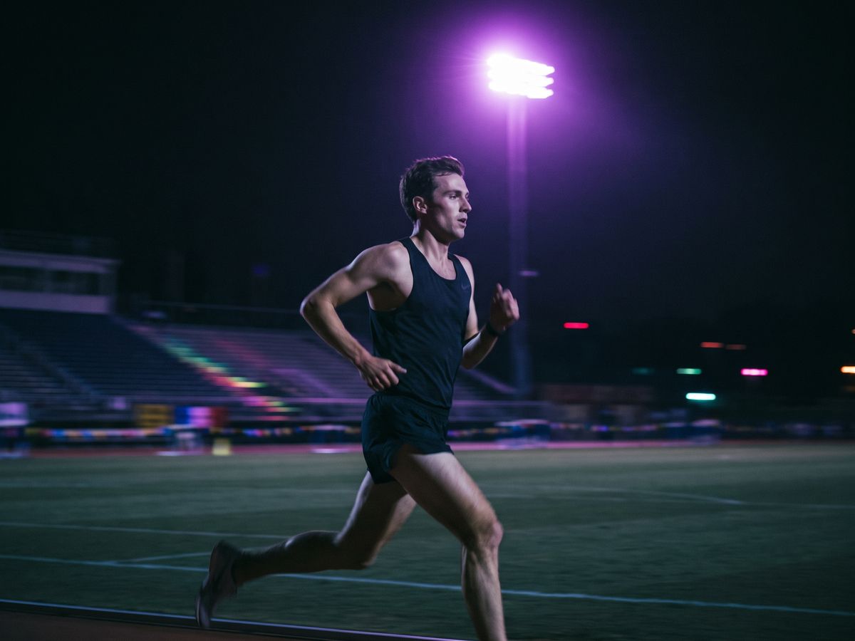 Coureur rapide sur une piste d'athlétisme de nuit